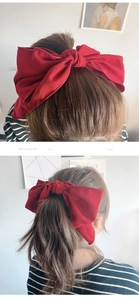 Macro detail of elegant oversized red fabric bow hair tie styled on a soft ponytail