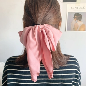 Elegant pink chiffon bow hair scrunchie with long ribbons shown on a model's ponytail