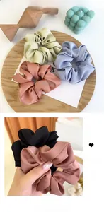Gros plan de chouchous en satin mat aux couleurs vert pastel, bleu, rose et noir doux