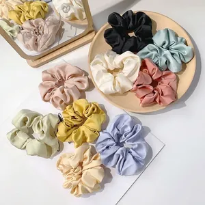 Lot de chouchous en soie aux couleurs pastel disposés sur une assiette en céramique