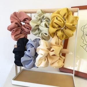 Lot de 7 chouchous colorés en tissu mat sur un support minimaliste en bois et métal blanc