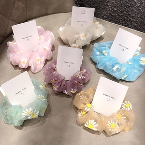 Detailed macro view of organza scrunchies featuring daisy patterns in multiple pastel colors
