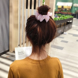 Detail of pink organza scrunchie with white daisy print worn on a bun hairstyle
