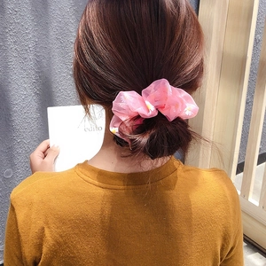 Detailed close-up of pink organza scrunchie with white daisy prints on a model