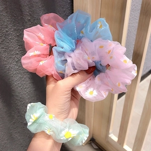 Detailed view of floral organza scrunchies with white daisy prints in pastel colors