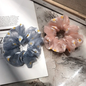 Detail of light blue and pink daisy pattern organza scrunchies on a marble background