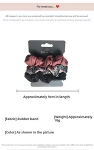 Detailed view of three silk satin hair scrunchies in pink, floral, and glossy black