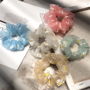 Close-up of five organza daisy flower scrunchies in pastel blue pink and yellow colors
