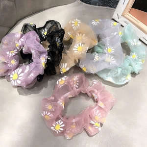 Detailed view of six colorful organza daisy flower print scrunchies in pastel tones