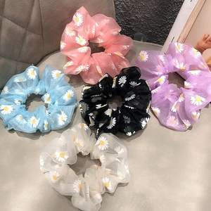 Detail view of five organza daisy flower scrunchies in pink, purple, blue, black, and beige