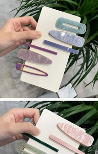 Dettaglio di fermagli per capelli in acetato marmorizzato e forcine glitterate su carta