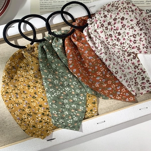 Gros plan de quatre chouchous à ruban floral en jaune, vert, orange et beige élégants