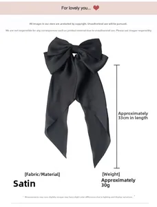 Détail d'un grand nœud à cheveux en satin noir avec de longs rubans de 33 cm et brillance