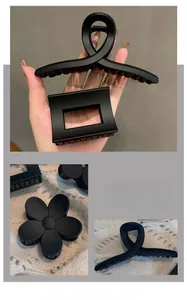 Macro shot of matte black hair claws in cross, rectangle, and floral shapes for women
