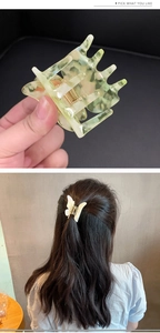 Detailed macro view of marbled butterfly hair claw clips in soft green and cream white