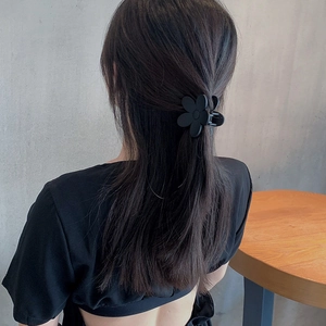 Elegant matte black flower hair claw clip for women in a stylish half-up hairstyle