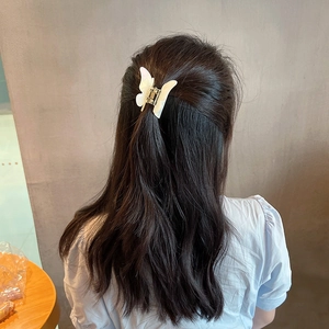 Elegant white butterfly hair claw clip for women, shown worn on long brown hair