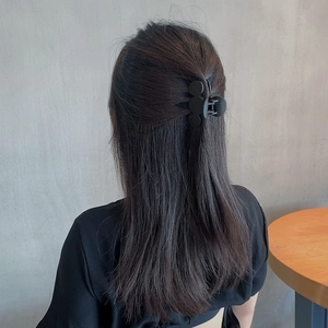 Matte black bow-shaped hair claw clip for women in a minimalist geometric flower design