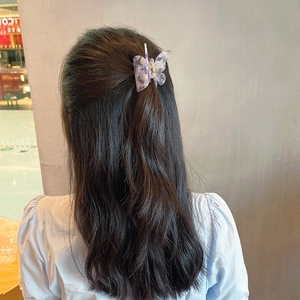 Elegant butterfly hair claw clip with purple marble texture on dark wavy hair style