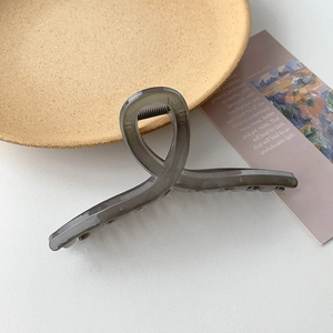 Minimalist translucent smoke grey hair claw clip with cross design on white desk