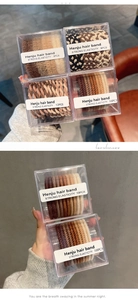 Neutral earth tone braided hair ties and plush scrunchies in transparent gift box packaging