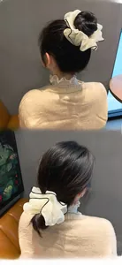 Dettaglio di un elastico gigante in organza bianca con bordo nero su chignon e coda bassa