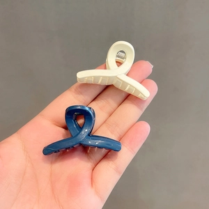 Solid color mini hair claws in cream and navy blue with a cross design for daily hair styling