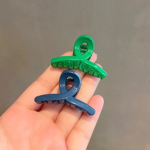 Mini solid color hair claws in vibrant green and navy blue with a glossy resin finish
