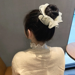 Scrunchie oversize in chiffon bianco panna con bordo nero indossato su uno chignon