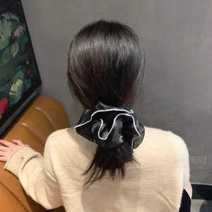 Elegante elastico per capelli in chiffon nero con bordo bianco indossato su una coda