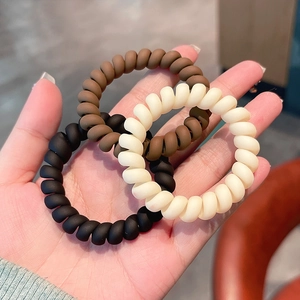 Three-piece spiral telephone cord hair ties in matte black, brown, and beige colors
