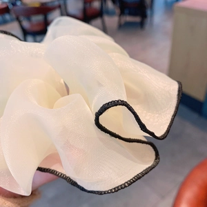 Scrunchie gigante in chiffon bianco con bordi ondulati neri e texture leggera