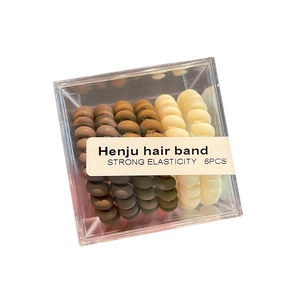 Set of six spiral telephone wire hair ties in earthy tones within a clear acrylic box