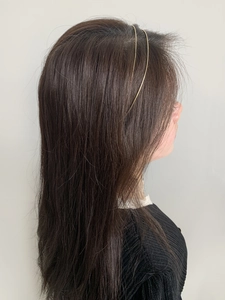 Detail view of thin double-layered golden metallic headband on model with long brown hair