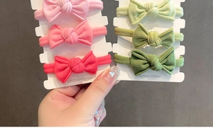 Sechser-Set bunte Baby-Stirnbänder mit gerippten Schleifen auf weißem Karton