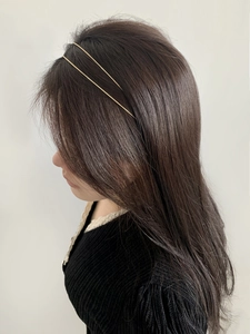 Detailed side view of a minimalist double-layered golden metal headband on hair