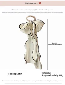 Détail du chouchou en satin blanc avec bordure noire, perles fantaisie et nœud de 34 cm