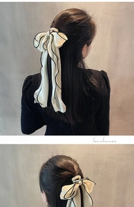 Détail du nœud à cheveux crème avec perles et bords plissés noirs sur tissu doux