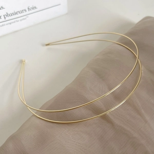 Elegant double-layered gold metal headband on champagne silk fabric background
