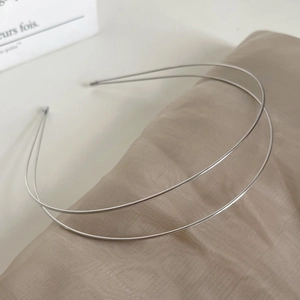 Minimalist double-layered silver metal headband displayed on elegant champagne silk fabric