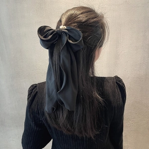 Chouchou élégant à grand nœud noir avec perle blanche porté par un modèle