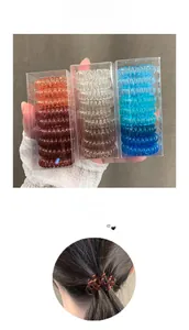 Gros plan d'un lot de trois boîtes d'élastiques spirales colorés pour cheveux en étuis