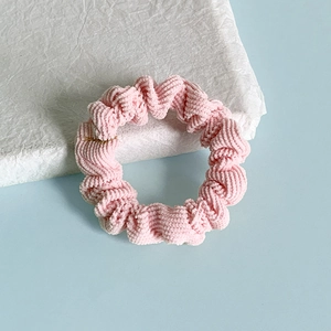 Détail d'un chouchou en velours côtelé rose avec texture plissée et matière épaisse