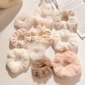 Lot de 9 chouchous en peluche aux tons Morandi chauds sur une surface crème douce