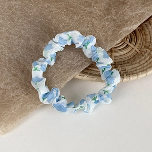 Detail eines geblümten Scrunchie mit blauem Muster auf leichtem weißem Stoff