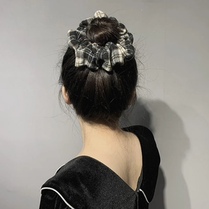 Classic black and white checkered scrunchie on a bun hairstyle with vintage French style