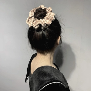 Soft houndstooth scrunchie in brown and beige knit fabric shown on a bun hairstyle