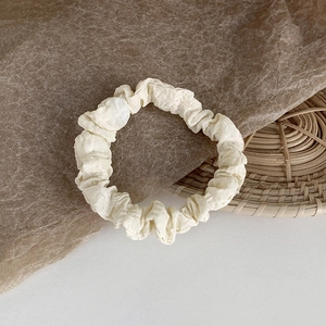 Detaillierte Makroansicht des beigen Scrunchies aus Faltenstoff mit hoher Elastizität