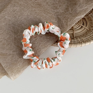 Detailaufnahme von Mesh-Haargummi mit orangem Blumenmuster auf weißem Hintergrund