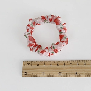 Florales Mesh-Haargummi mit roten Rosenmustern und Lineal zum Größenvergleich auf Weiß